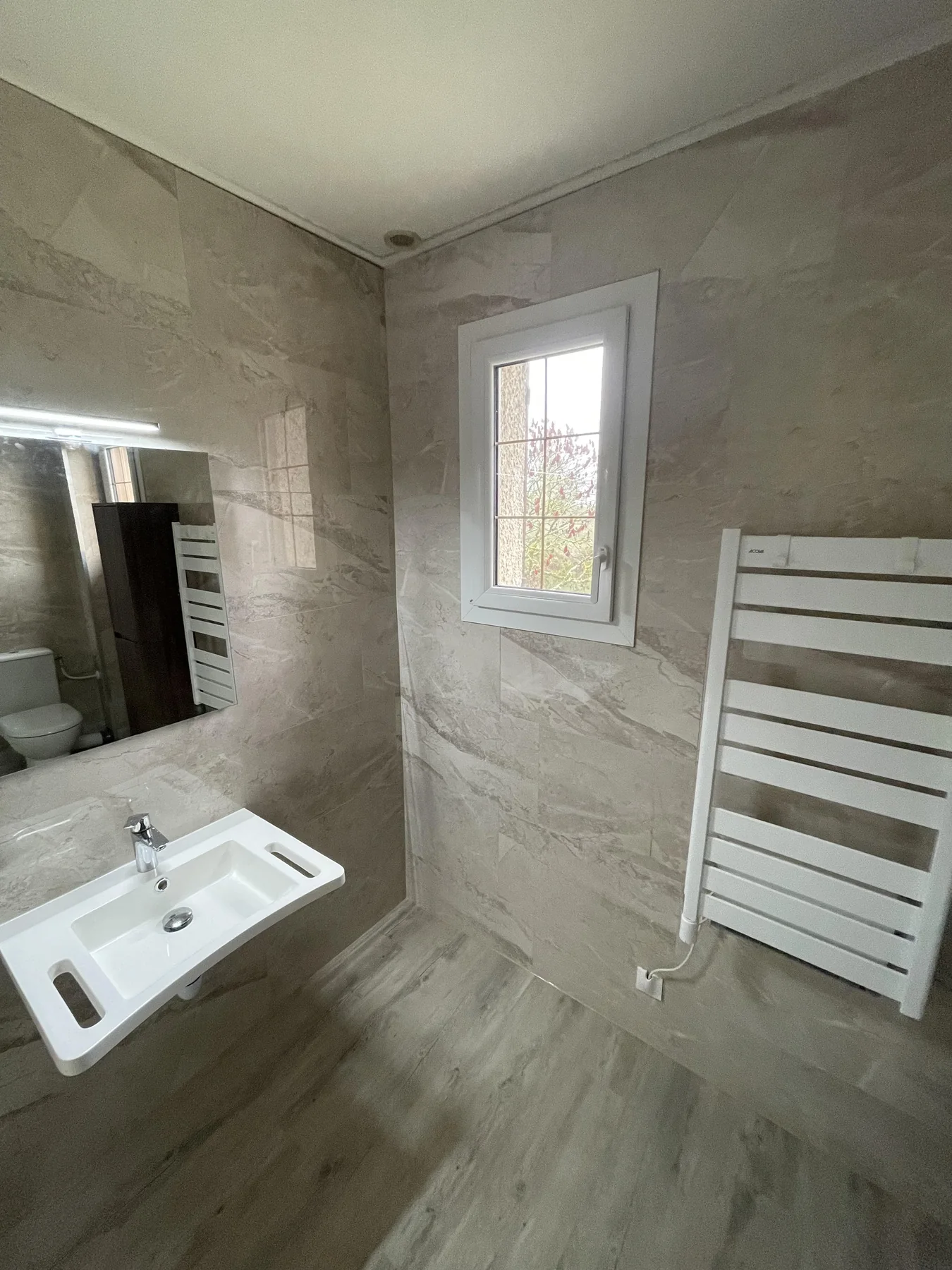Vasque suspendue et sèche-serviettes dans une salle de bains beige