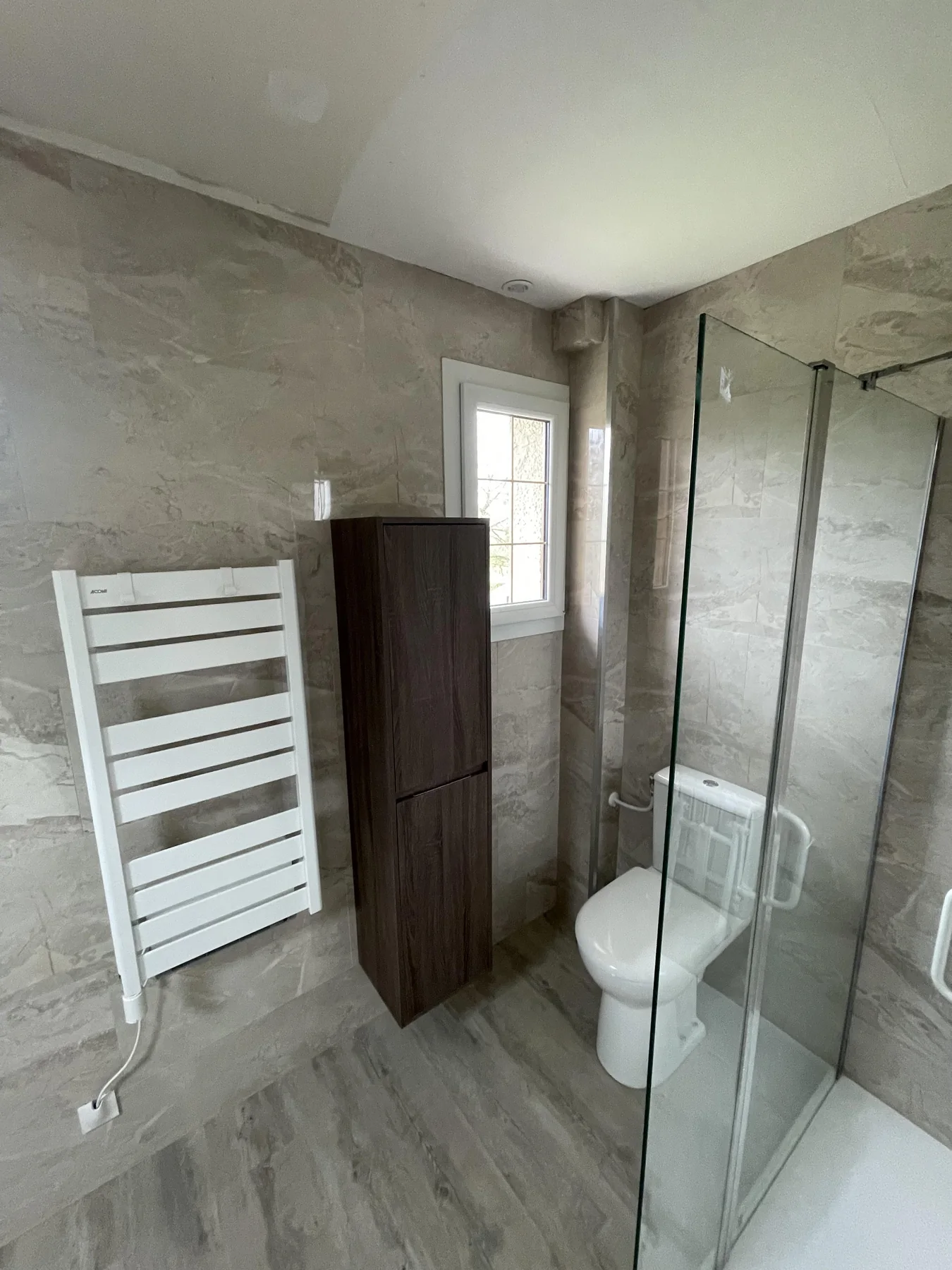 Rangements et paroi vitrée dans une salle de bains beige